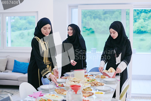 Image of young muslim girls serving food on the table for iftar dinner
