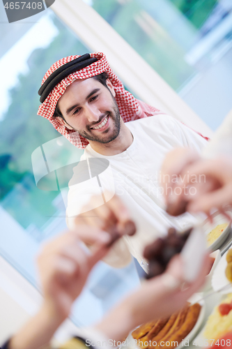 Image of Muslim family having Iftar dinner eating dates to break feast