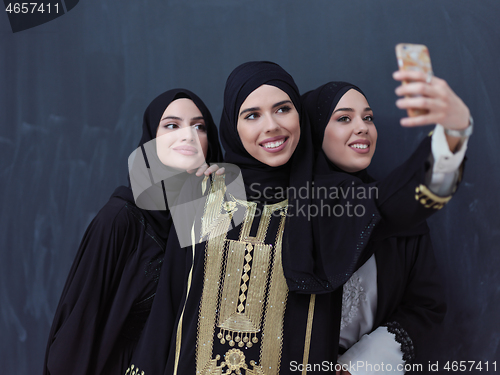 Image of muslim women taking selfie picture in front of black chalkboard