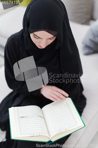 Image of young muslim woman reading Quran at home