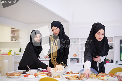 Image of young muslim girls serving food on the table for iftar dinner