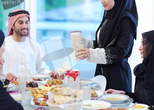 Image of Muslim family having Iftar dinner drinking water to break feast