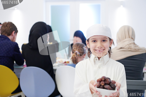 Image of little muslim boy holding a plate full of sweet dates