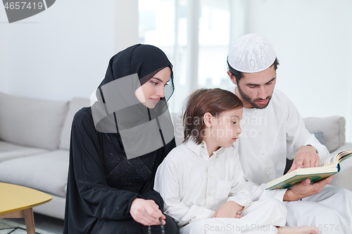 Image of muslim family reading Quran and praying at home