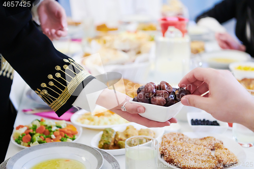 Image of Muslim family having Iftar dinner eating dates to break feast