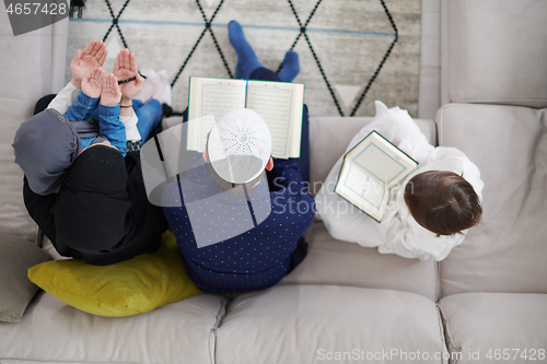 Image of muslim family reading Quran and praying at home top view