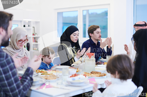 Image of traditional muslim family praying before iftar dinner