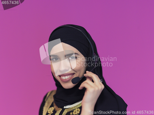 Image of portrait of muslim woman with headset on pink background