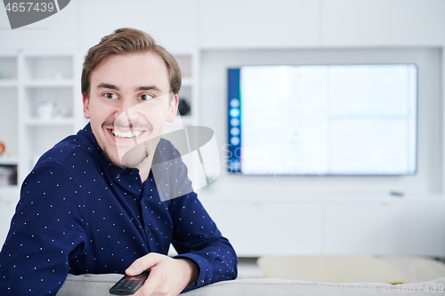 Image of young man watching tv at big modern home