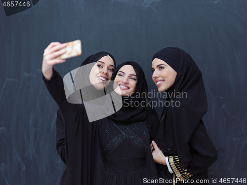 Image of muslim women taking selfie picture in front of black chalkboard