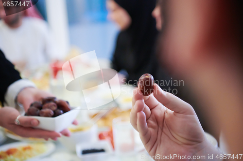 Image of Muslim family having Iftar dinner eating dates to break feast