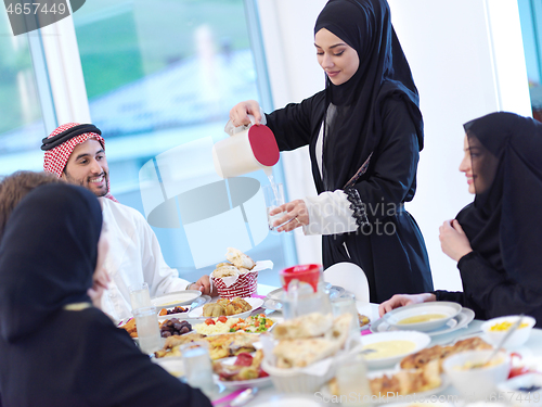 Image of Muslim family having Iftar dinner drinking water to break feast