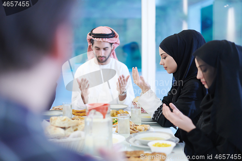 Image of traditional muslim family praying before iftar dinner