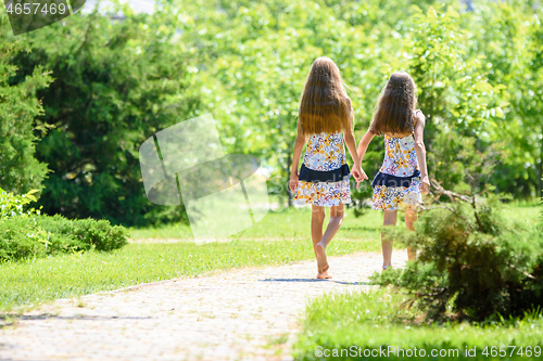 Image of Two girls walk along a path in a beautiful city park