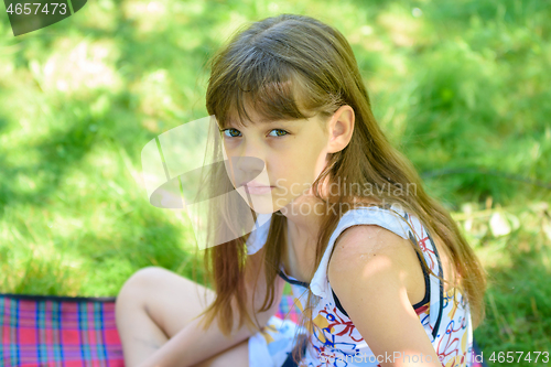 Image of Portrait of a little sad girl on a picnic in a green park