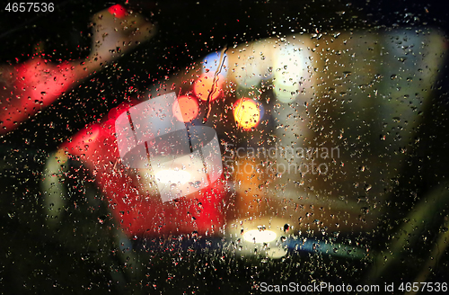 Image of Lights of night city through the glass of the car with raindrops