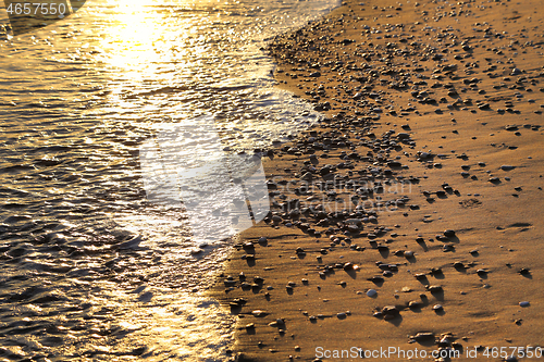 Image of Seashore with pebbles on a sandy beach in the rays of sunlight