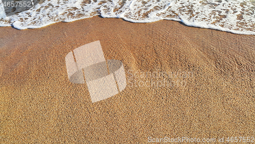 Image of Sandy beach background with white foam of sea wave 