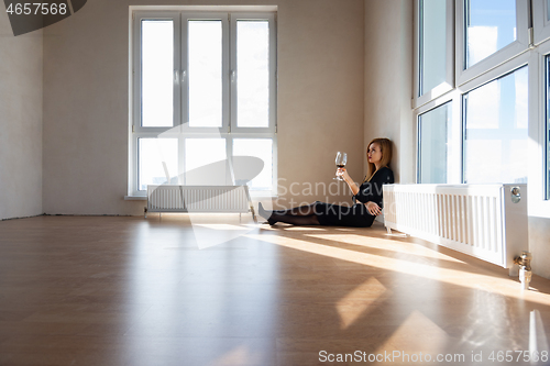 Image of Beautiful elegant girl sits on the floor in a large light room with stained glass windows
