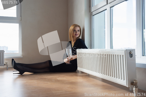 Image of girl with a beautiful smile and a glass of wine sitting on the floor