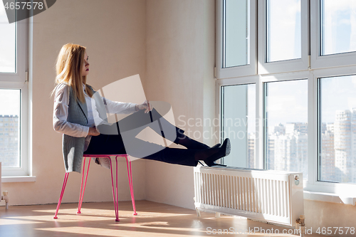 Image of empty room with a girl sitting on a chair in front of the window