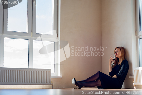 Image of sad girl sits on the floor in an empty room with large stained glass windows