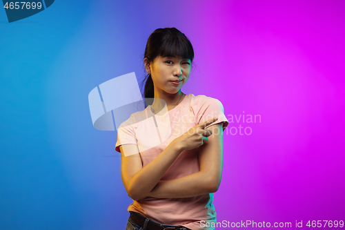 Image of Asian young woman\'s portrait on gradient studio background in neon