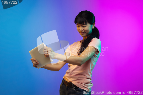 Image of Asian young woman\'s portrait on gradient studio background in neon