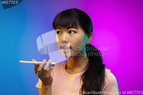 Image of Asian young woman\'s portrait on gradient studio background in neon