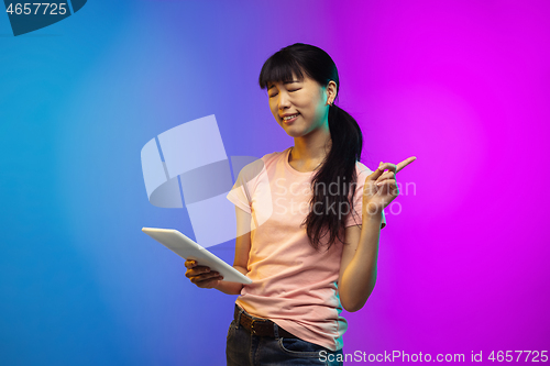 Image of Asian young woman\'s portrait on gradient studio background in neon