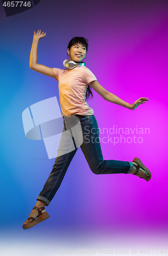 Image of Asian young woman\'s portrait on gradient studio background in neon