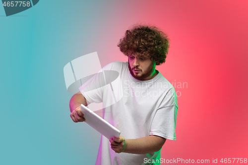 Image of Caucasian young man\'s portrait on gradient studio background in neon