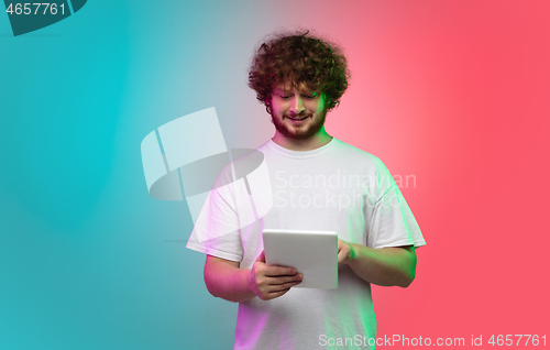 Image of Caucasian young man\'s portrait on gradient studio background in neon