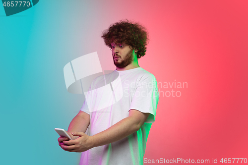 Image of Caucasian young man\'s portrait on gradient studio background in neon