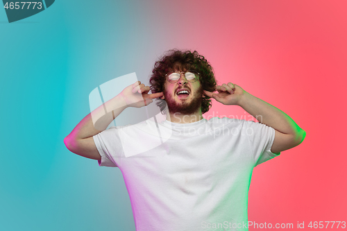 Image of Caucasian young man\'s portrait on gradient studio background in neon