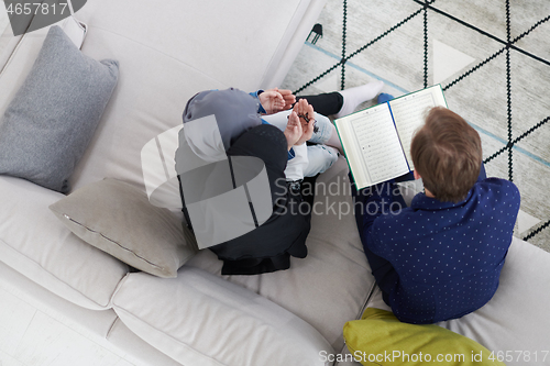 Image of muslim family reading Quran and praying at home top view