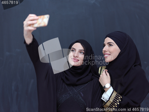 Image of muslim women taking selfie picture in front of black chalkboard