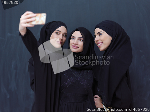 Image of muslim women taking selfie picture in front of black chalkboard