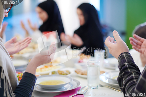 Image of traditional muslim family praying before iftar dinner