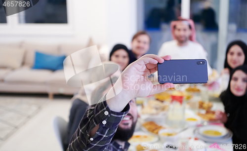 Image of Muslim family having Iftar dinner taking pictures with mobile ph