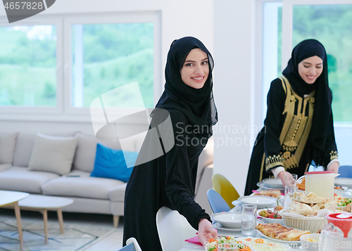 Image of young muslim girls serving food on the table for iftar dinner