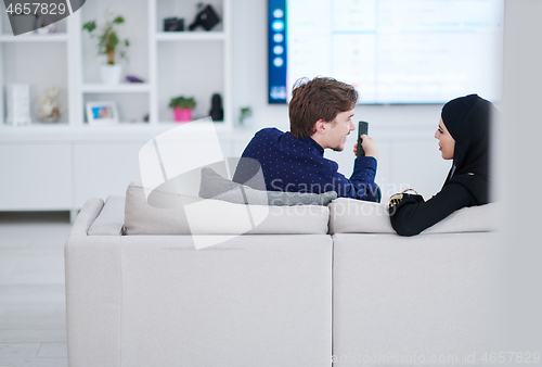 Image of young muslim couple watching TV together
