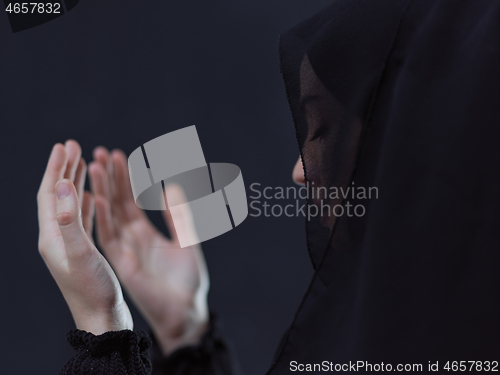 Image of muslim woman making traditional prayer to God in front of black 