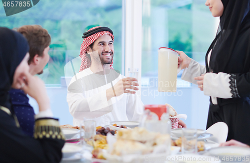 Image of Muslim family having Iftar dinner drinking water to break feast