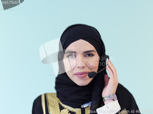 Image of portrait of muslim woman with headset on cyan background