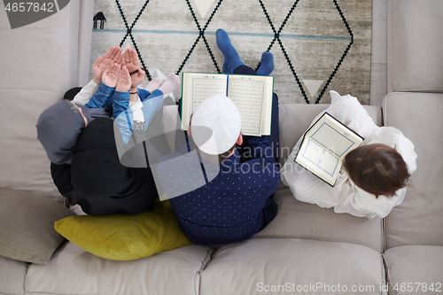 Image of muslim family reading Quran and praying at home top view