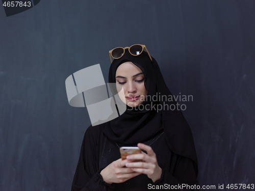 Image of young muslim woman wearing sunglasses using smartphone