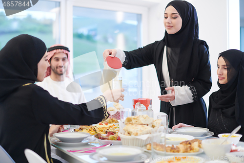 Image of Muslim family having Iftar dinner drinking water to break feast