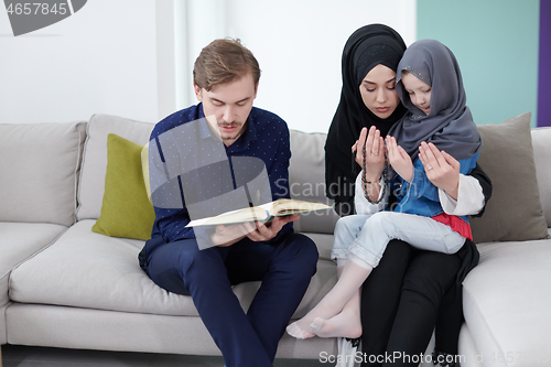 Image of muslim family reading Quran and praying at home