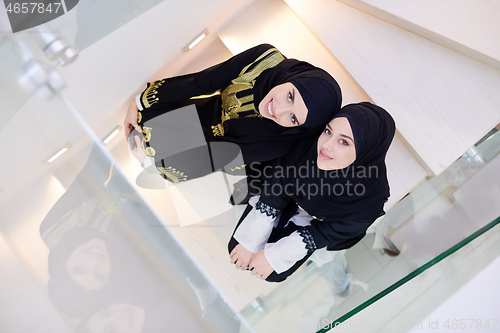 Image of portrait of beautiful muslim women sitting on wooden stairs at h